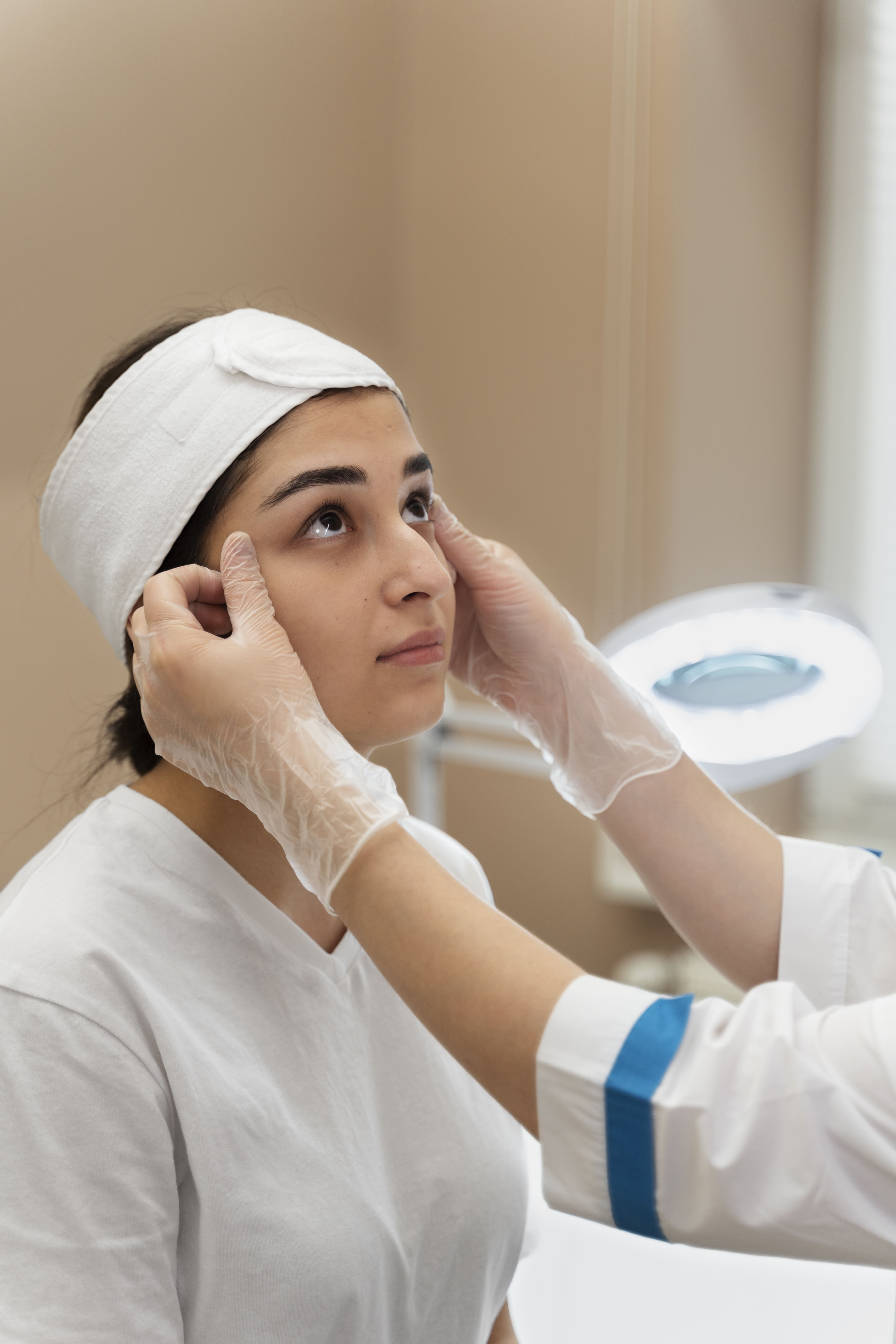Clinician in gloves preparing a patient’s face for a cosmetic skin treatment in a spa setting