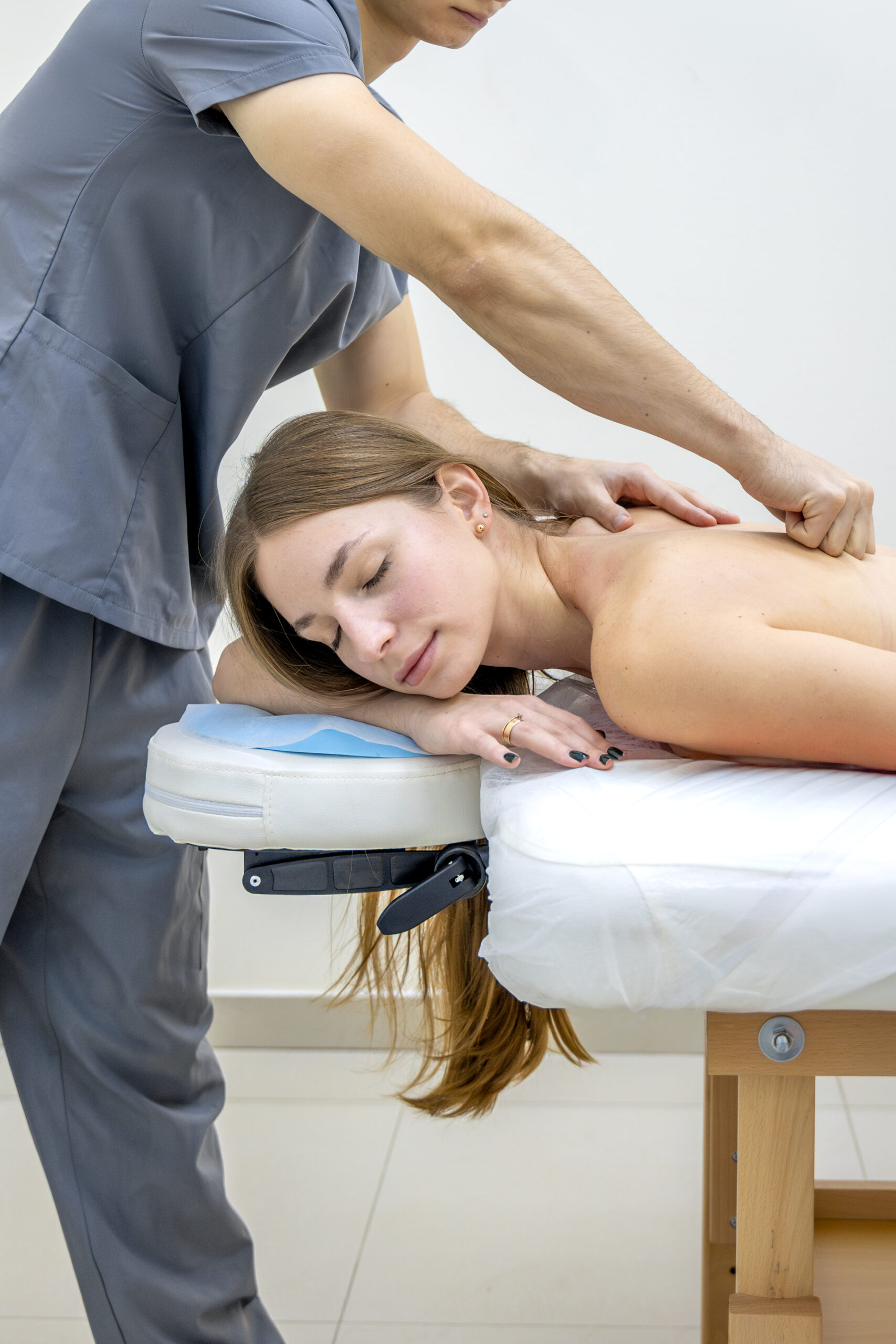 Massage therapist applying pressure to a client’s upper back and shoulders during a session